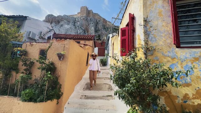 Fashion model business woman in a sun hat exploring the streets of Anafiotika, Plaka in Athens, Greece