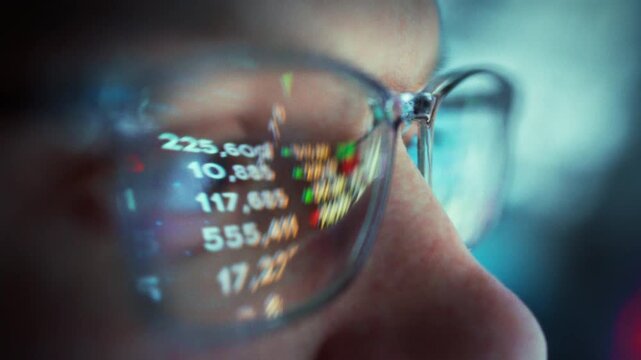 A stock analyst in glasses sits at his computer in a night-time office, monitoring the stock exchange with real-time data. His lenses reflect fluctuating numbers as he analyzes stocks