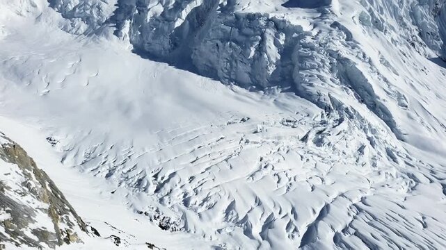 Slow sweeping shot across a pristine snowscape, highlighting the textures of ice, snow, and rock in a remote and extreme mountain environment.	