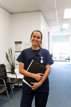 Portrait of a tall young lady in scrubs holding a clinic record