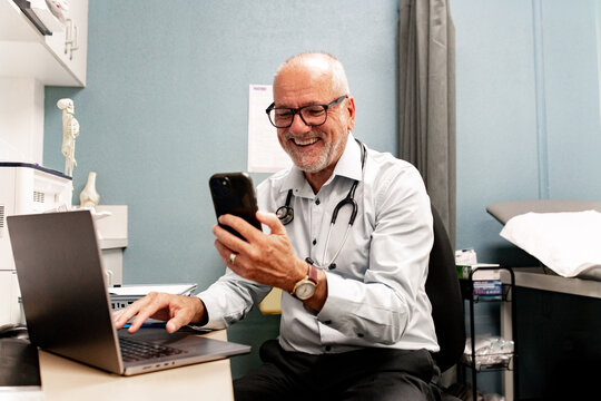 Healthcare professional multitasking with laptop and smartphone in clinic