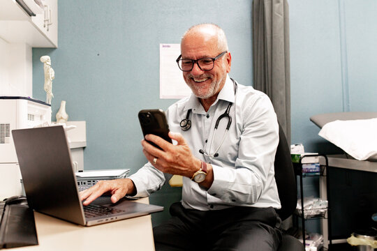 Healthcare professional smiling at smartphone during clinic work