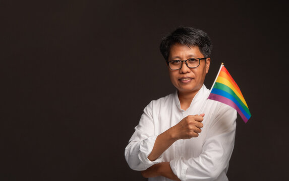 Confident businesswoman holding rainbow pride flag in studio