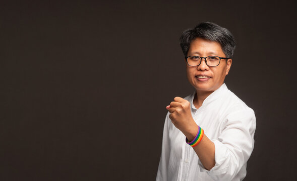 Confident businesswoman with rainbow wristband fist gesture