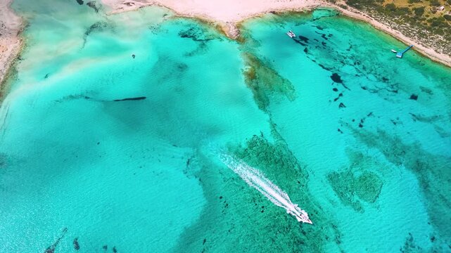Epic aerial of Balos Lagoon with speedboat crossing turquoise water. Cinematic reveal of Tigani rock, Gramvousa island and mountain peak with moving clouds. Complete Mediterranean landscape, 4k.