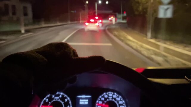 Secluded urban roads illuminated by tail lights, Silent night journey captured with steering wheel and dashboard lights, Quiet city streets at night as driver follows luminous tail lights carefully 