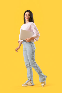 Female programmer with laptop on yellow background