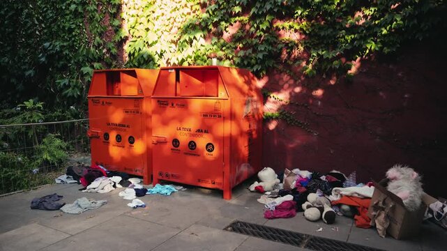 Overflowing trash bins with clothes, piles of unwanted clothes lying, clothing bins in the city, a company sort the clothes to be sold or recycled. High quality 4k footage