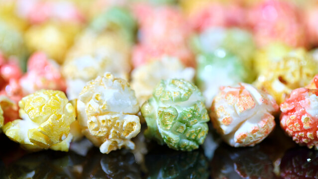 Colorful popcorn in various flavors displayed on a black surface during a snack gathering