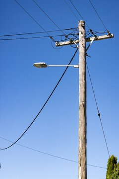 Wooden power pole with street light showing electric wires and insulators.