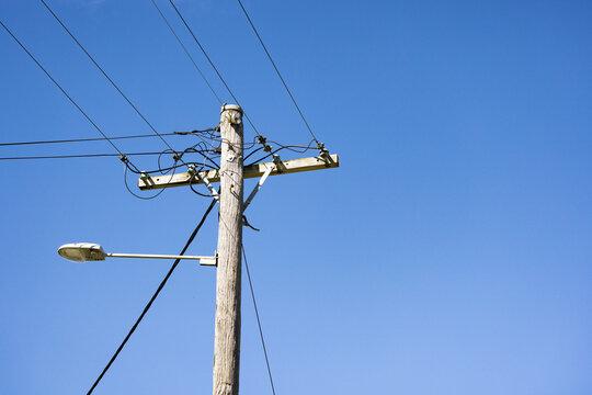 Wooden power pole with street light showing electric wires and insulators.