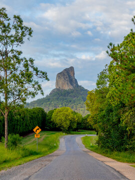 Sealed road through green bushland leading to mountain peak in background