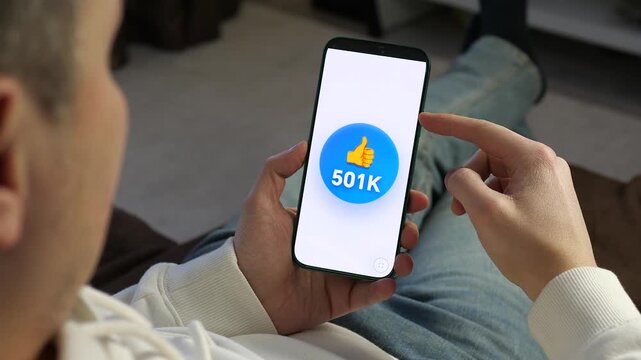 A person watching a viral post gain likes on a smartphone. Thumbs up counter increases from 440K to 551K. Perfect for content about digital success, viral marketing, and influencer growth. High-impact