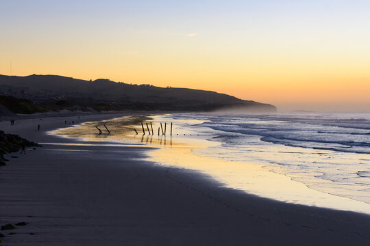 Colourful dawn over beach with reflections, the sea and mist in the distance