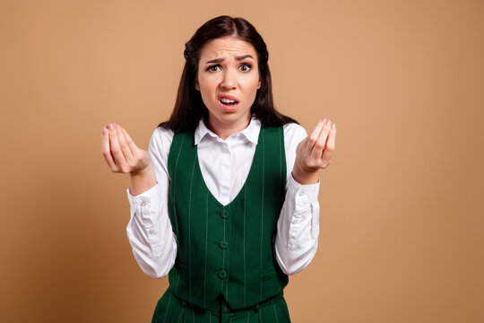 Confused businesswoman making a questioning hand gesture with a frustrated, disbelieving expression in a green suit conveying confusion and exasperation