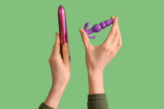 Woman with vibrator and anal plug from sex shop on green background