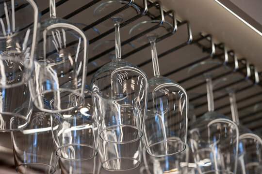 Group of wine glasses hanging upside down above a bar rack in pub or restaurant. Glasses for wine on a bar with serving items.