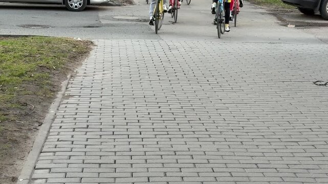 Rear view cyclists cobblestone pavement approaching, urban commute scene with group riding across uneven stone surface, visible