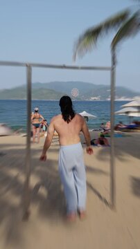 Barechested Individual Strides Towards Camera. Man Without Shirt Approaches Camera On Sunny Beach. Sunlit Beach Scene Features Shirtless Man Confidently Strolling Towards Camera With Relaxed Demeanor