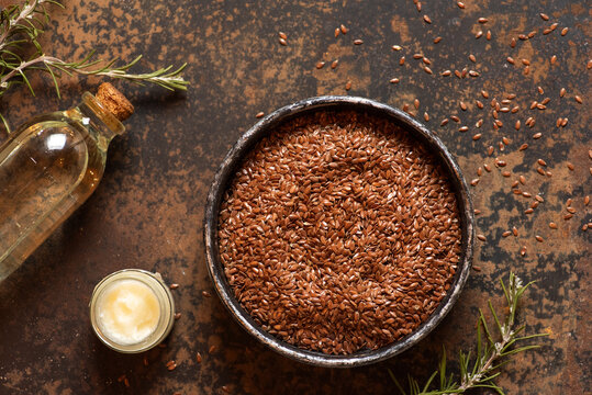 Flaxseeds in Bowl with Oil and Butter on Rustic Table