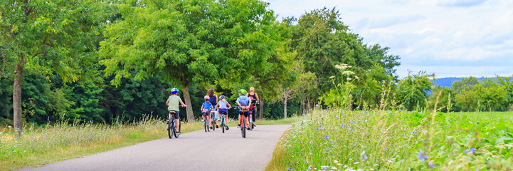 Obraz premium Group of people riding bicycles on a path through trees and fields in the daytime