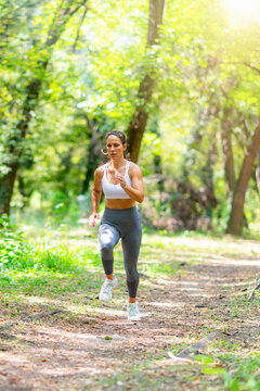 Fit woman running on forest trail in natural environment during outdoor workout, healthy lifestyle, fitness and wellness concept.