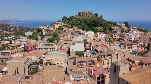 Wide view of the Mediterranean village of Begur, featuring the density of terracotta roofs and the surrounding green hills of Costa Brava.