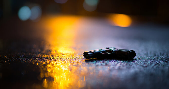 Handgun lying on wet street at night