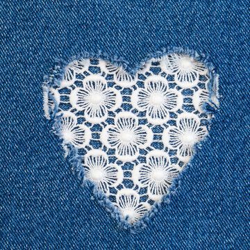 Heart-shaped patch made of white fabric sewn onto blue denim, highlighting a creative repair technique used in clothing
