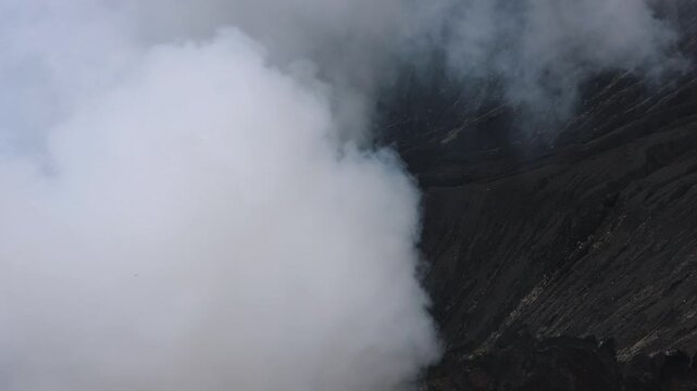 A dramatic volcanic landscape dominated by massive clouds of thick white steam rising from an active crater Mount Bromo in East Java, Indonesia  