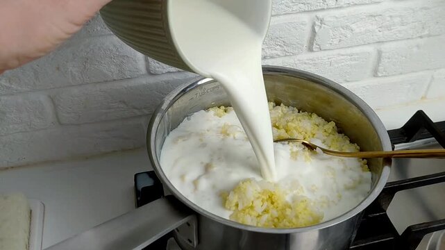 The process of cooking porridge on the stove, pouring milk