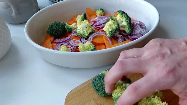 The vegetables are spread out and mixed in a baking dish. Cooking turkey, broccoli, carrot and onion fricassee with cream