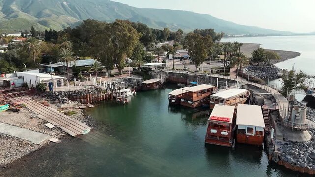 Aerial Drone view of tour boats docked at Ein Gev harbor, Sea of Galilee, over the Kinneret shoreline and Golan Heights backdrop