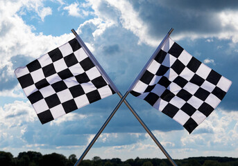 Fototapeta premium A black and white checkered flag flutters against a clear blue sky background to symbolize the finish of a high-speed Formula 1 racing competition and the success of the winner