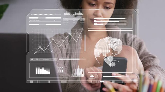 Woman tapping smartphone and updating HUD globe and charts while analyzing business data on laptop