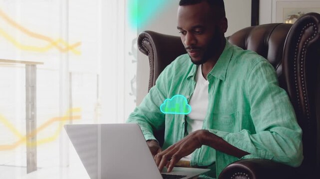 Mid-adult man typing on laptop by window, causing teal clouds and yellow waves showing cloud sync
