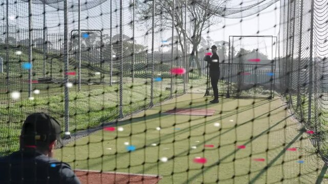 Catcher nodding, pitcher winding, throwing balls through net into mitt during baseball practice