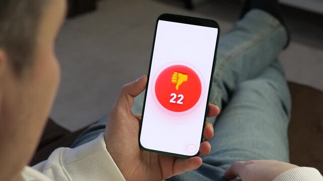 Cinematic shot of a person watching a dislike counter skyrocket on their smartphone. A red icon rapidly increases from 1 to 203. Powerful visual for cyberbullying, negative feedback, and social media