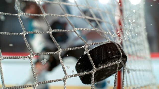 An ice hockey puck hitting the back of the net