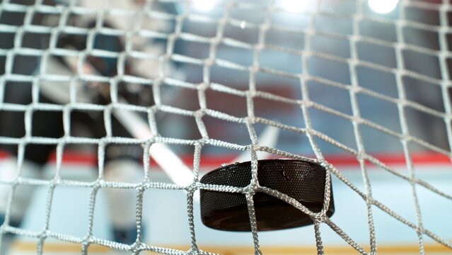 An ice hockey puck hitting the back of the net