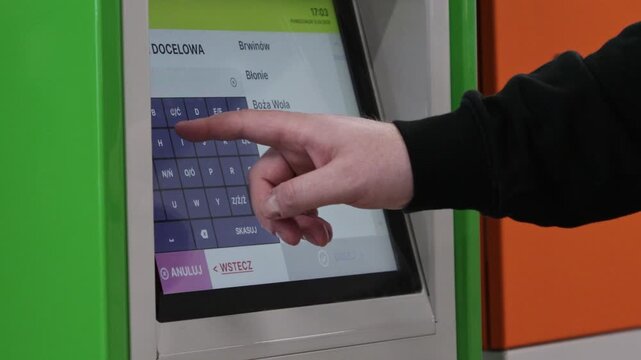 A person uses a touchscreen ticket machine interface to search for a transit destination, highlighting modern self-service technology and convenient travel planning in urban transport