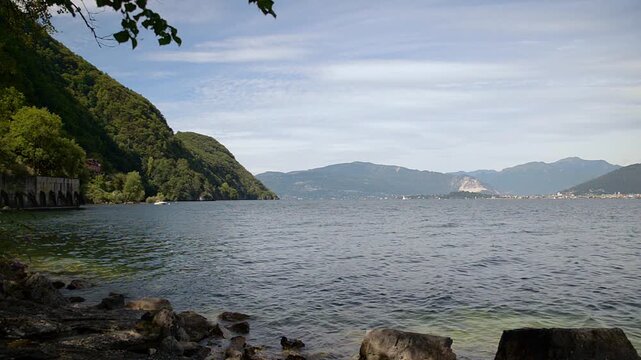 Lake Maggiore panoramic landscape with Mottarone mountain, Italian Alps, sunny summer day, blue sky with white clouds, rippled water, northern Italy scenic view between Laveno and Cald&egrave;, no people