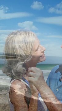 Vertical video: Senior couple swaying after woman's smile man touching cheek seaside overlay travel