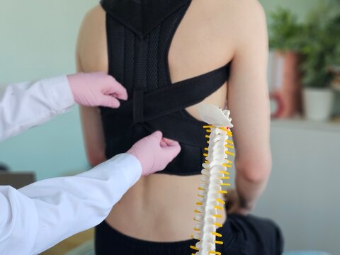 Doctor adjusts spinal support on patient in clinic setting during treatment