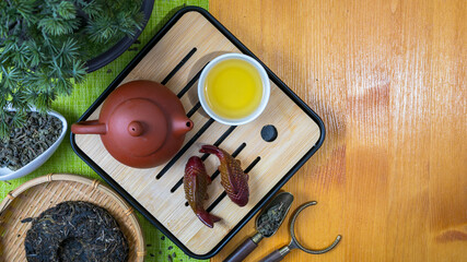 Obraz premium Traditional Chinese tea ceremony with clay teapot and cup on wooden chaban tray. Top view set of pu-erh tea, tea pet fish, and organic dried leaves for healthy lifestyle meditation