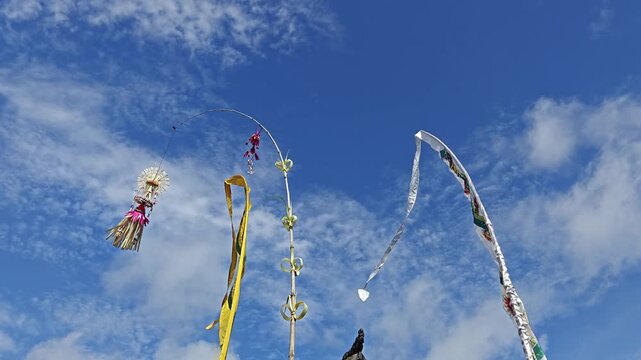 Traditional Balinese Penjor Decorations Under Clear Blue Sky with Cirrus Clouds