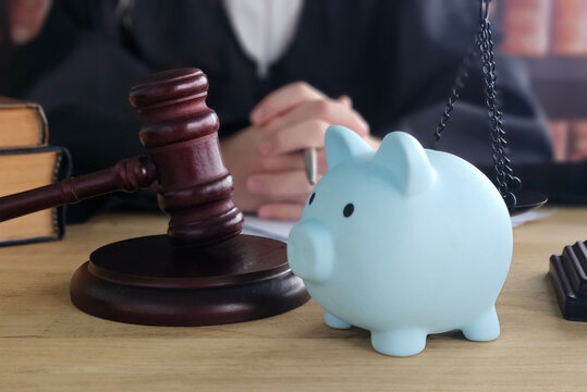 Court scene showing judge's gavel and a piggy bank on table