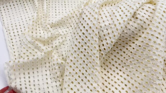 A high quality white perforated mesh fabric is showcased, highlighting its intricate hole pattern, lightweight texture, and flexible drape for apparel and industrial design applications.