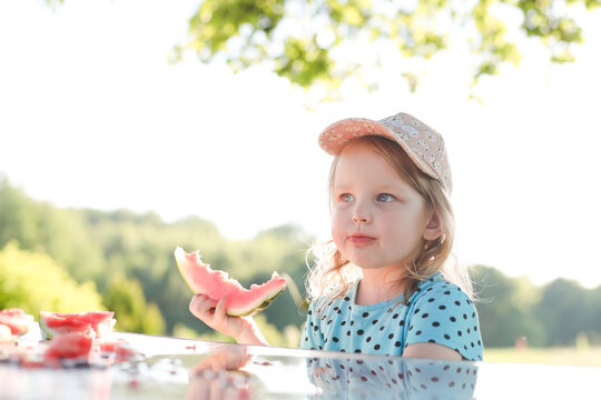 cute little girl eating watermelon outdoors in summertime. Child and watermelon in summer. 