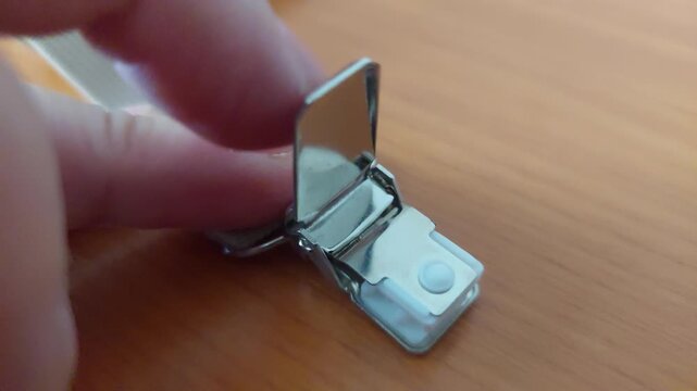 Close-up of a metal suspender clip being opened and closed